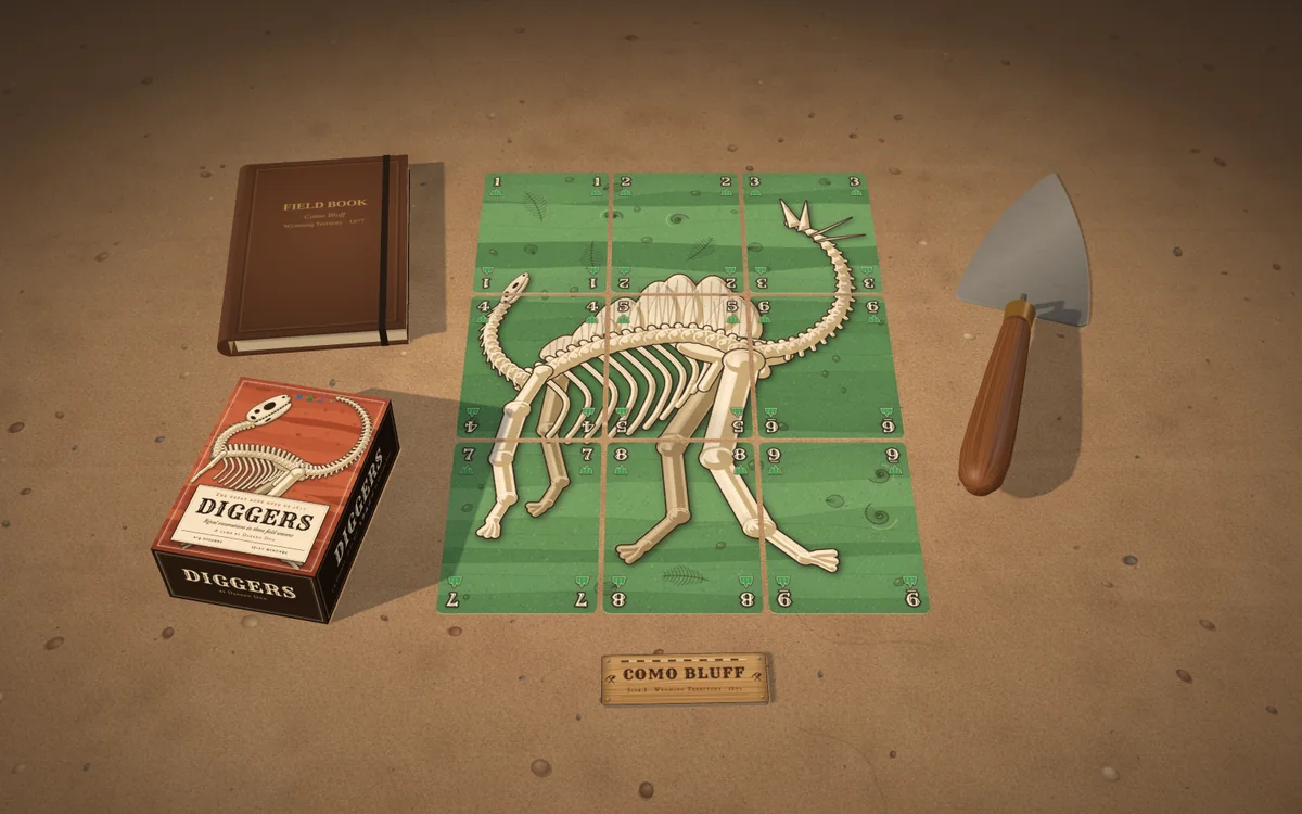 Diggers mockup on sandstone at a dig site: the tuck box, a field book, a whole Stegosaurus laid out as nine cards, the Como Bluff dig-site strip and a trowel.